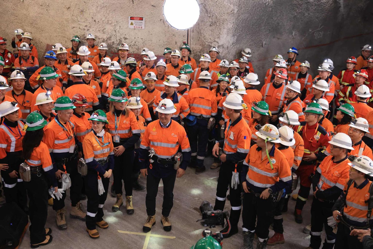 Group of miners posing underground with helmets and safety gear.